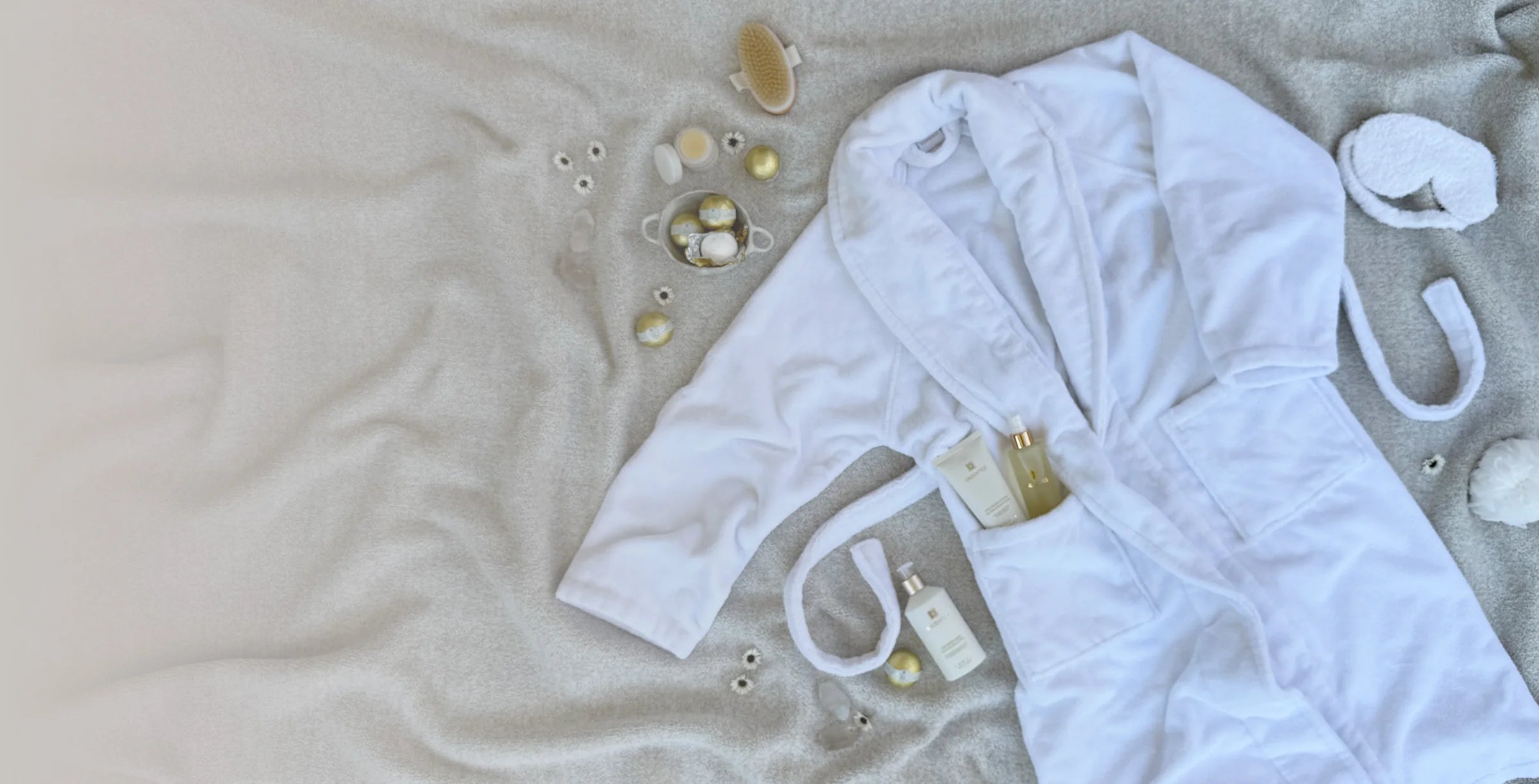 A white Kashwére robe and spa accessories arranged with ZENTS bath and body products