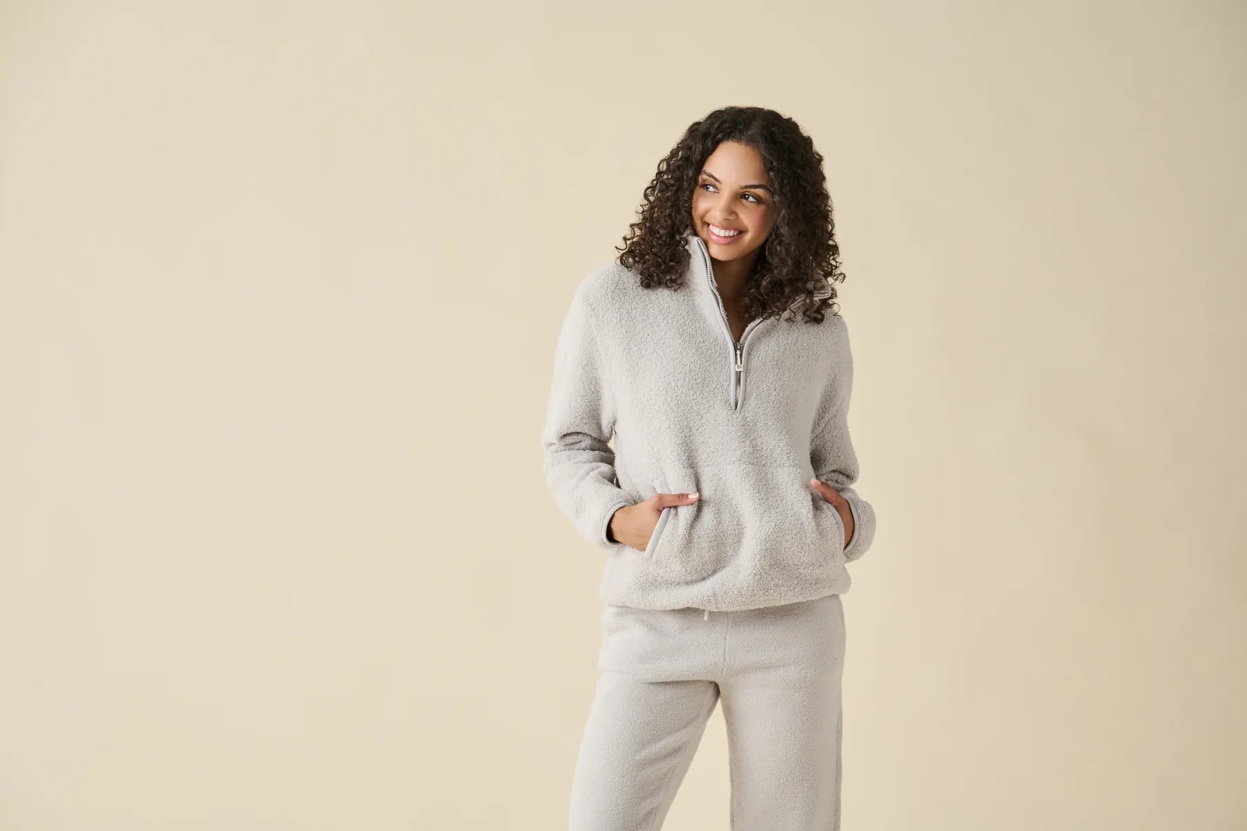 A woman wearing a soapstone Kashwére half-zip pullover and joggers